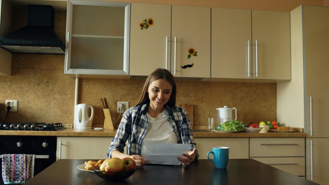 Žena čte dokumenty v kuchyni